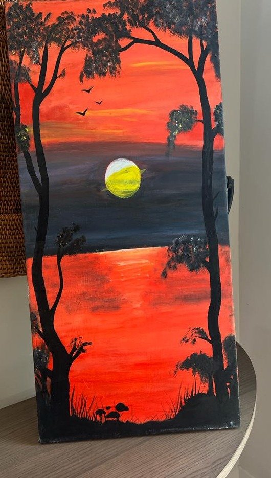 African sunset landscape, silhouetted trees against an orange and indigo sky reflected in water